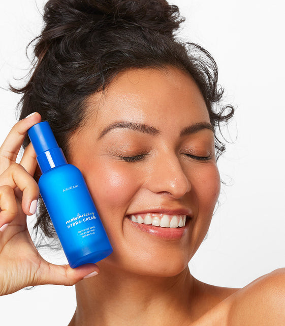 Model holding AAVRANI Moisturizing Hydra-Cream next to face
